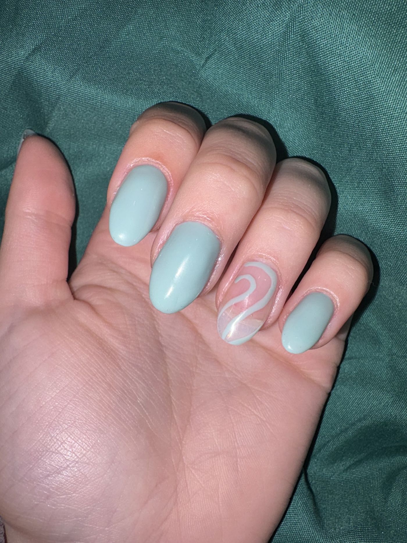 Mintgroene amandelnagels met een witte swirl op één nagel